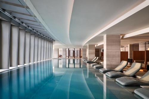 a swimming pool with lounge chairs and windows at Rosewood Guangzhou in Guangzhou