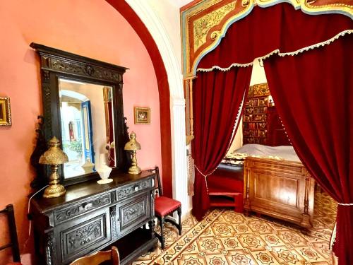 1 dormitorio con espejo y 1 cama con cortinas rojas en Dar Aziz en Sousse