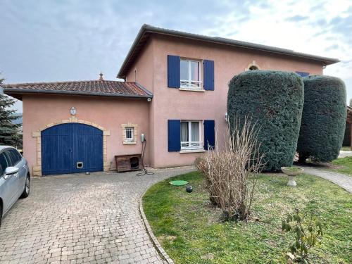 une maison avec un garage bleu et deux grands arbres dans l'établissement Maison privatisée avec piscine et jardin 4 chambres, à Sain-Bel