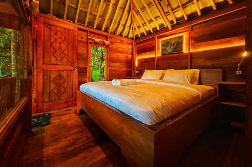 a bedroom with a bed in a wooden cabin at Aulia Bungalows in Tetebatu