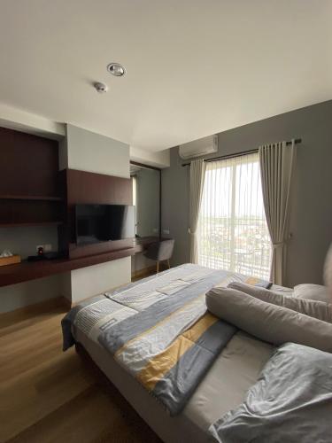 a bedroom with a large bed and a window at The Yudhistira Tower by Asoka in Yogyakarta