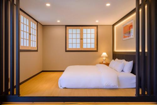 a bedroom with a white bed and two windows at Hotel HaruSida in Seogwipo