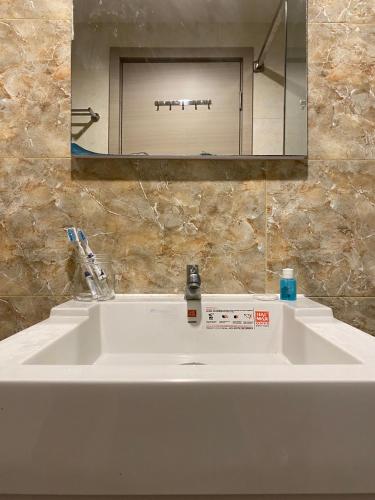 a white sink in a bathroom with a mirror at The Yudhistira Tower by Asoka in Yogyakarta