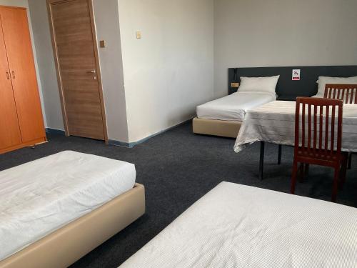 a room with two beds and a table and chairs at Destiny Hotel in Harhorin