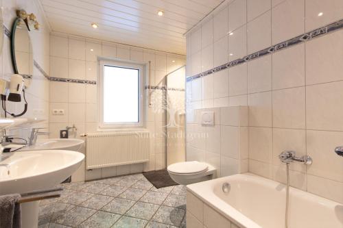 baño blanco con lavabo, bañera y aseo en Pension Büürma, en Papenburg
