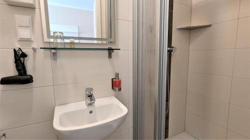a white bathroom with a sink and a shower at Altstadthotel Goldene Kugel in Waren