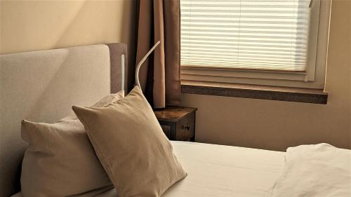 a bed with two pillows and a window in a room at Altstadthotel Goldene Kugel in Waren
