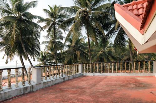 a balcony of a resort with palm trees and the ocean at The Coastal Relic by EWA Properties in Padubidri