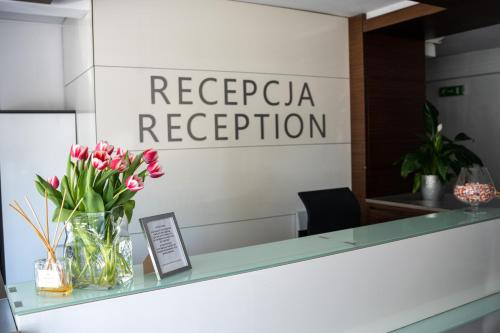 a glass counter with a vase of flowers on it at Aparthotel Strefa Premium in Tychy