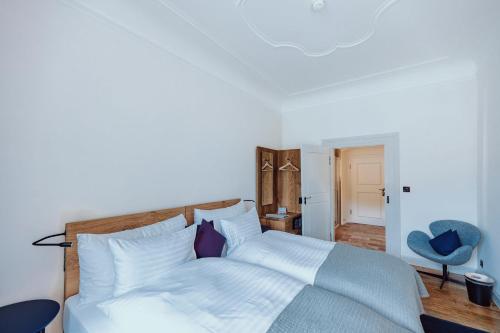 a bedroom with a bed and a blue chair at Hotel Kloster Fischingen in Fischingen