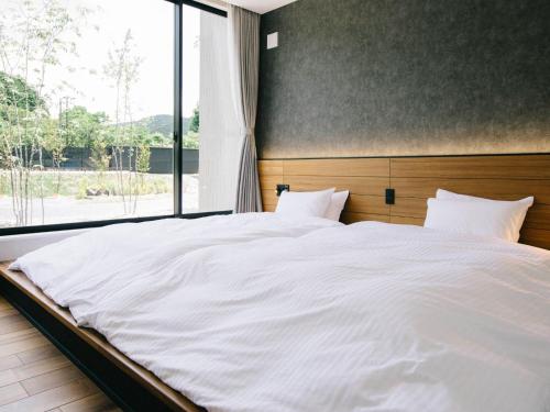 Schlafzimmer mit einem großen weißen Bett und einem großen Fenster in der Unterkunft TEF TANIGUMI - Vacation STAY 78908v 