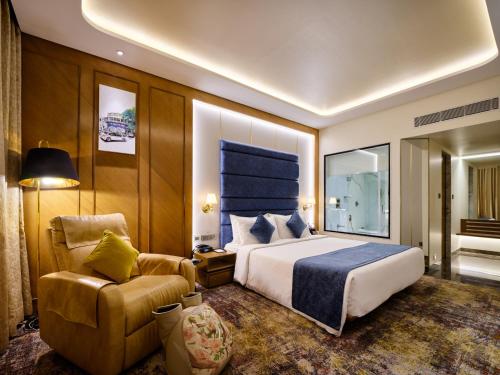 Pokój hotelowy z łóżkiem i krzesłem w obiekcie Sayaji Pune w mieście Pune