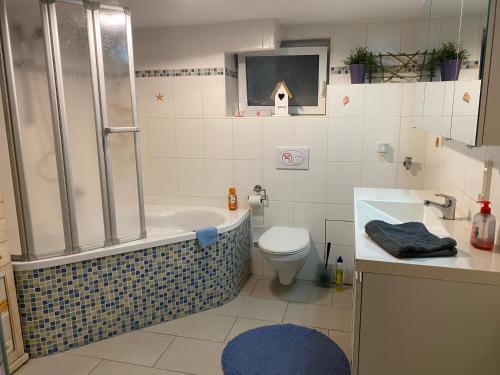y baño con bañera, aseo y lavamanos. en House Apartment am See en Markkleeberg