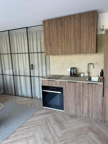 a kitchen with wooden cabinets and a sink and a dishwasher at Apartamentai Palangos Kopos in Palanga