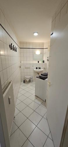 ゴータにあるFewo 5の白いタイル張りのバスルーム(トイレ、シンク付)