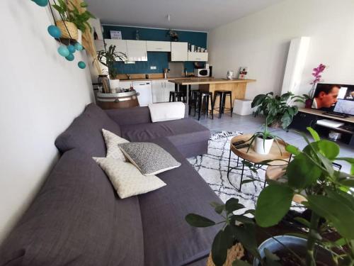 Il comprend un salon avec un grand canapé et une cuisine. dans l'établissement Appartement moderne 6 personnes terrasse et jardin, à Castelnau-le-Lez