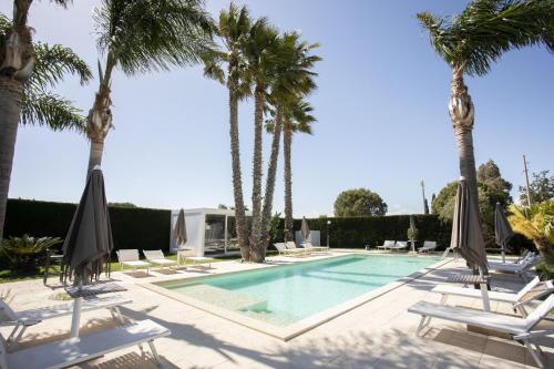 - une piscine bordée de palmiers et de chaises longues dans l'établissement Villa Dalesco, à Leverano