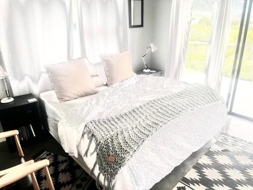a bedroom with a bed with white sheets and a window at 3 Indigo in Hermanus
