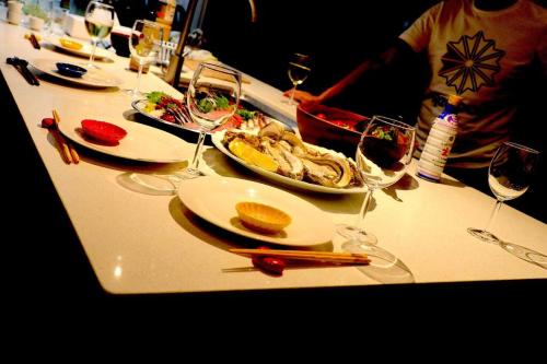 a table with plates of food and glasses of wine at コースタルキャビン - シービュー バーベキュー ピザ サウナ プール ホットタブ - Coastal Cabin Chiba - Seaview BBQ PIzza Sauna Pool Hot-tub in Iwada