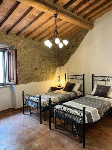 two beds in a room with a stone wall at Casa Bella Vista in Pereta