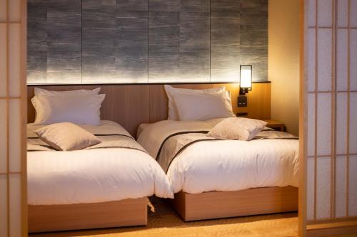 two beds in a hotel room with white pillows at Biwako Ryokusuitei in Otsu