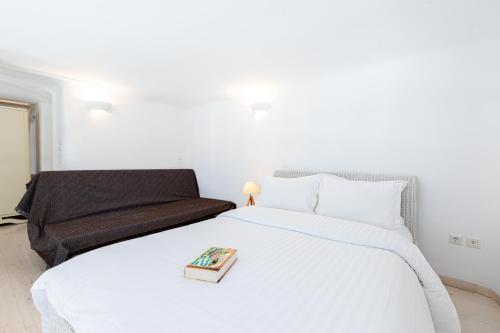 a bedroom with a white bed and a couch at Villa Thelgo Mykonos in Psarou