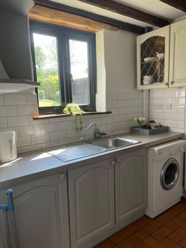 a kitchen with a sink and a washing machine at The Stables, Moulton St Mary in Norwich