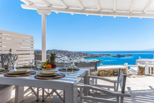 a table on a balcony with a view of the ocean at Villa Thelgo Mykonos in Psarou