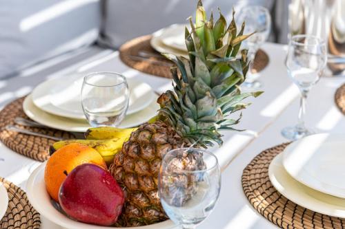 a plate of fruit on a table with plates and glasses at Villa Thelgo Mykonos in Psarou