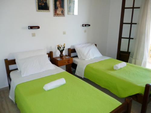 two beds in a room with green sheets at Villa Helen in Arillas