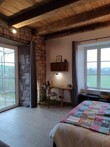 une chambre avec un lit, une table et des fenêtres dans l'établissement Chambres d'hôtes Ancien Presbytère de Saint-Mayme, à Onet le Château