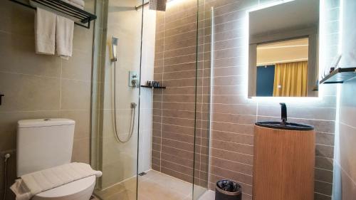 ein Bad mit einer Dusche, einem WC und einem Spiegel in der Unterkunft Kozi Nest in Kuching