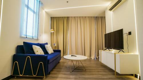 uma sala de estar com um sofá azul e uma televisão em Kozi Nest em Kuching