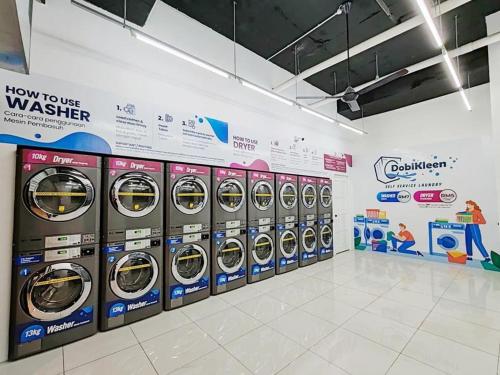 uma fila de máquinas de lavar e secar numa loja em Kozi Nest em Kuching