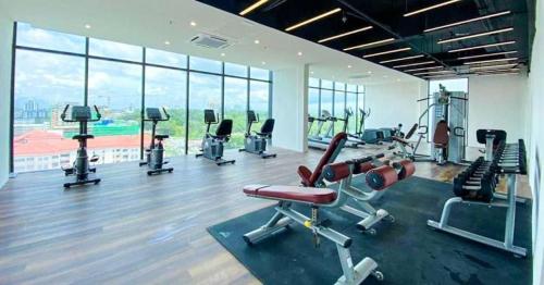 einen Fitnessraum mit Kardiogeräten in einem großen Raum mit Fenstern in der Unterkunft Kozi Nest in Kuching