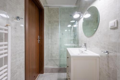 uma casa de banho com um lavatório e um chuveiro com um espelho. em Pokoje "Przy Porcie" nad morzem em Darłowo