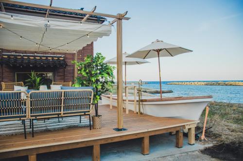 a wooden deck with a boat and an umbrella at インフィニティ露天風呂 蔵サウナ オーシャンビュー 一棟貸切 Sea Side 椿 in Sado