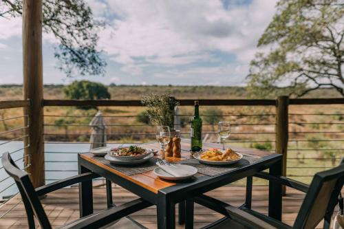 uma mesa com dois pratos de comida e uma garrafa de vinho em Mdluli Safari Lodge em Hazyview