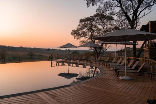 a wooden bridge with benches and umbrellas over a lake at Mdluli Safari Lodge in Hazyview
