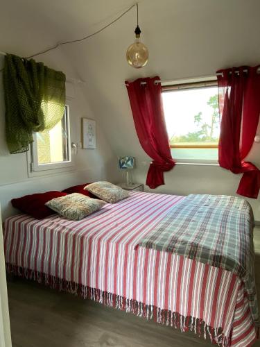 une chambre avec un lit avec des rideaux rouges et une fenêtre dans l'établissement Studio 2 personnes Nid Cocooning Calme grand confort, à Perros-Guirec