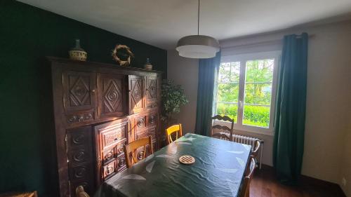 a dining room with a table and a large wooden cabinet at LA TANIÈRE in Gueures