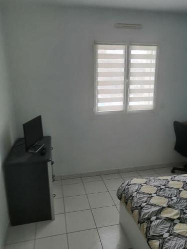 une chambre avec un lit et un bureau et deux fenêtres dans l'établissement Chambre proche du mont Saint Michel, à Montours