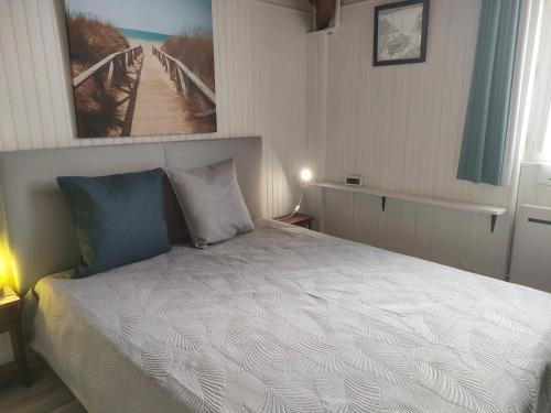 une chambre avec un lit blanc avec un tableau sur le mur dans l'établissement Ref 031 T3 mezzanine vue mer à louer pour 4-6 personnes, à Arzon