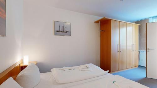 a bedroom with a white bed and a wooden cabinet at a cappella 01 im Binz, strandnahe FeWo mit Schwimmbad im Haus, in Binz
