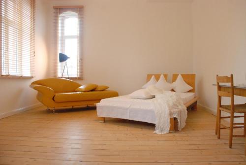 a bedroom with a bed and a couch and a chair at Sweet Clementine B & B in Hannover