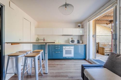 a kitchen with blue cabinets and a table and chairs at Appartement avec terrasse/Bord de mer/Idéal SURF in Seignosse