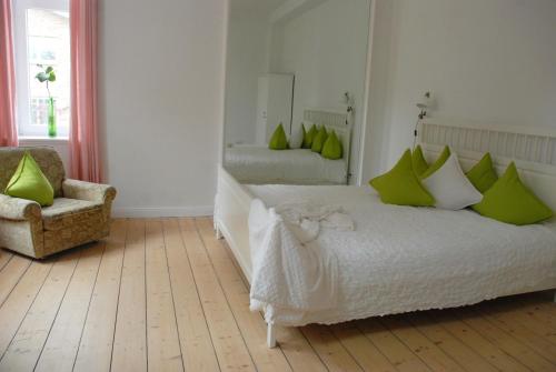 a bedroom with a bed with green pillows and a chair at Sweet Clementine B & B in Hannover