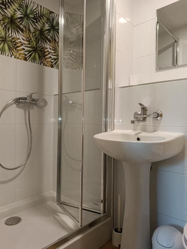 a white bathroom with a sink and a shower at Pod Jaskółką in Ustka