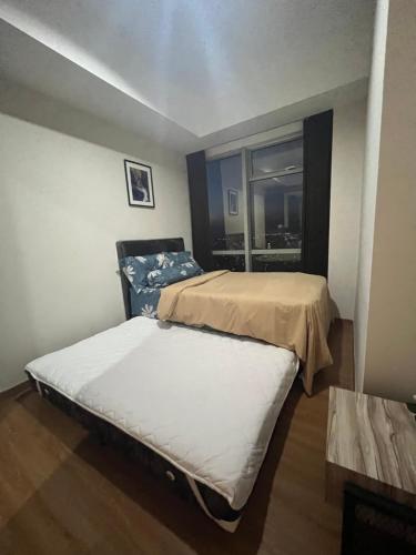 two beds in a small room with a window at DeAr Caspian Apartment in Surabaya