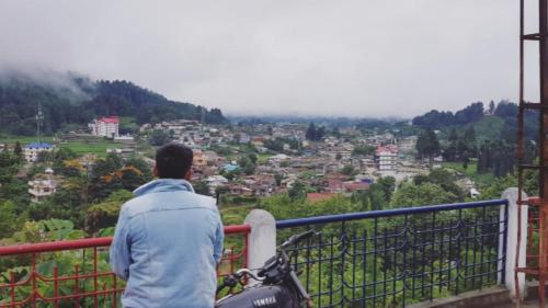 a man standing on a balcony looking at a city at Arunachal Guest house in Hāpoli